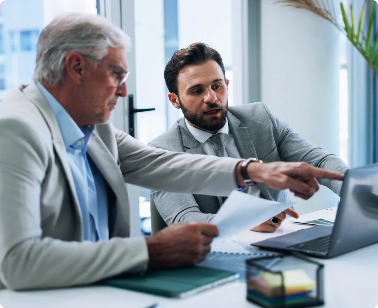 Two businessmen discussing work at laptop